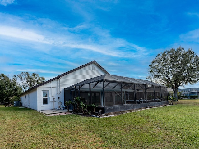 rear view of house featuring glass enclosure, a patio area, a yard, and central AC unit