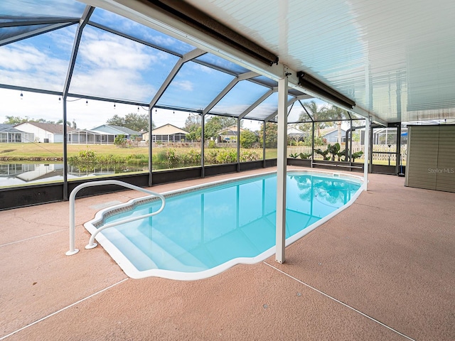 view of pool featuring a water view, glass enclosure, and a patio area