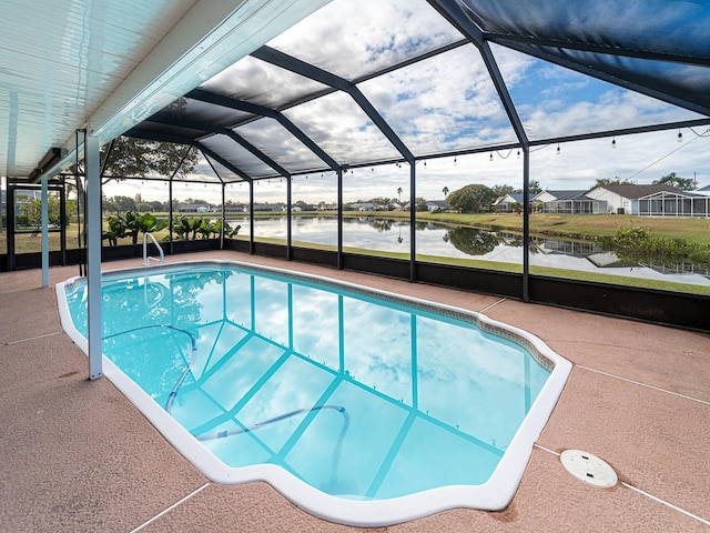 view of pool featuring glass enclosure, a patio area, and a water view