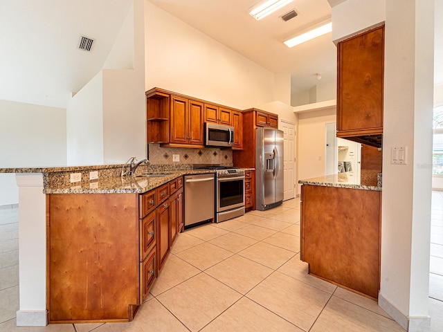1515 Lions Club Dr, Brandon, FL 33511 - kitchen featuring appliances with stainless steel finishes, a sink, a peninsula, light stone counters, and high vaulted ceiling