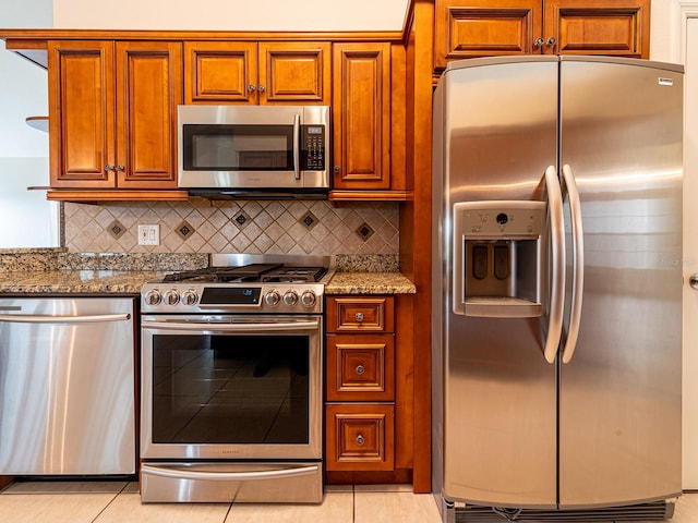 1515 Lions Club Dr, Brandon, FL 33511 - kitchen with appliances with stainless steel finishes, stone countertops, brown cabinetry, decorative backsplash, and light tile patterned floors