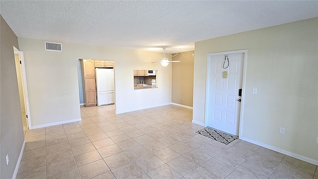 interior space featuring ceiling fan, light tile patterned flooring, and a textured ceiling