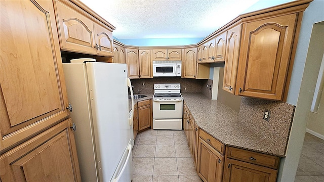 kitchen featuring tasteful backsplash, a textured ceiling, light tile patterned floors, and white appliances