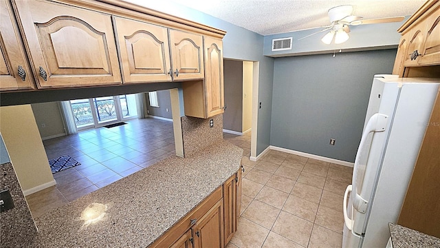 kitchen with ceiling fan, white fridge, light tile patterned flooring, and a textured ceiling