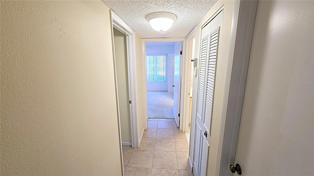 corridor with light tile patterned floors and a textured ceiling