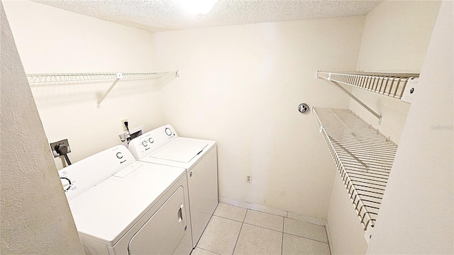 laundry area with separate washer and dryer, a textured ceiling, and light tile patterned floors