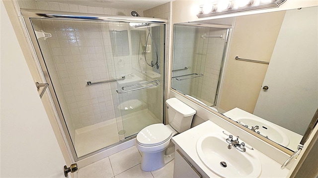 bathroom with tile patterned floors, a shower with door, vanity, and toilet