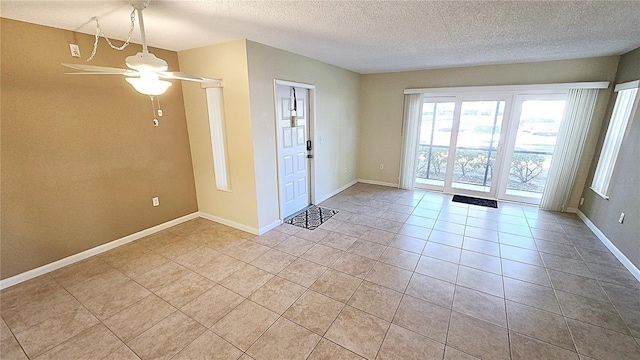 interior space with ceiling fan, light tile patterned flooring, and a textured ceiling