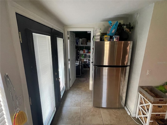 kitchen featuring stainless steel fridge, vaulted ceiling, and light tile patterned floors