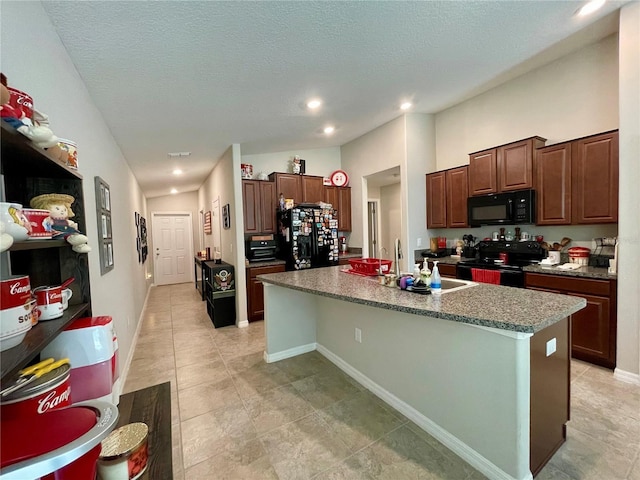 kitchen with a center island with sink, black appliances, a textured ceiling, and sink