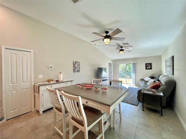 dining space with a textured ceiling, vaulted ceiling, ceiling fan, and light tile patterned flooring