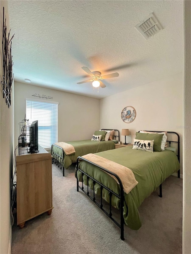 bedroom with a textured ceiling, carpet floors, and ceiling fan