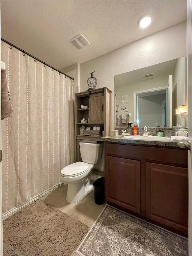 bathroom with vanity, toilet, and a textured ceiling