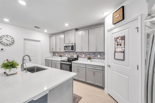 kitchen featuring backsplash, a textured ceiling, stainless steel appliances, sink, and gray cabinets