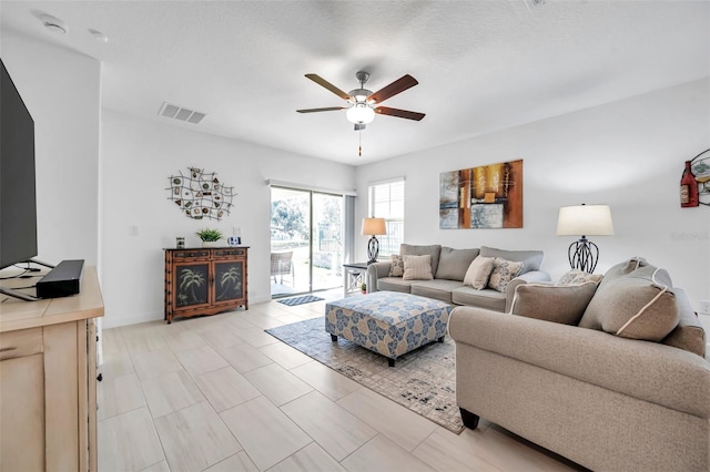 living room featuring ceiling fan and a textured ceiling