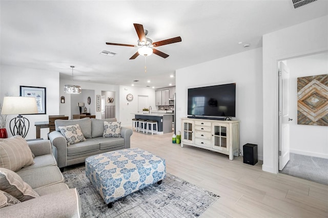 living room featuring ceiling fan, sink, and light wood-type flooring