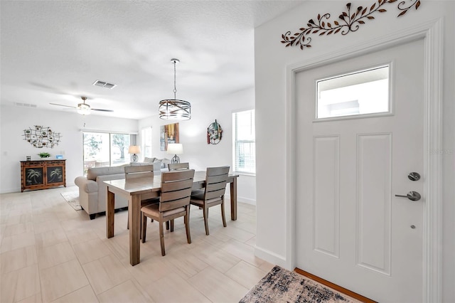 dining room featuring a textured ceiling and ceiling fan with notable chandelier