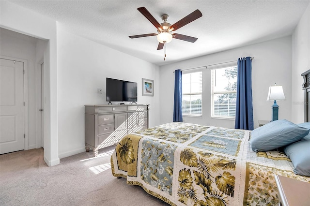 bedroom featuring ceiling fan, light colored carpet, and a textured ceiling