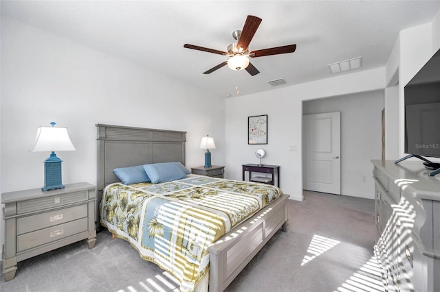 bedroom with ceiling fan, light colored carpet, and a textured ceiling