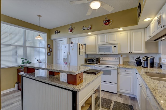 kitchen with light stone countertops, pendant lighting, white appliances, and white cabinetry