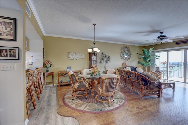 dining area with ceiling fan with notable chandelier, light hardwood / wood-style floors, crown molding, and a textured ceiling