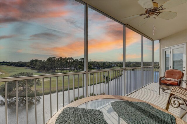 balcony at dusk with ceiling fan and a water view