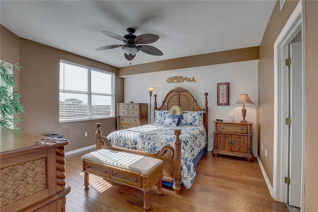 bedroom with a textured ceiling, light hardwood / wood-style flooring, and ceiling fan