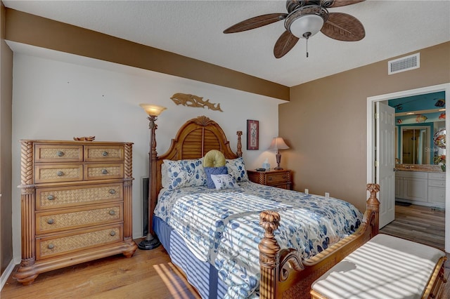 bedroom featuring ensuite bath, ceiling fan, a textured ceiling, and light wood-type flooring