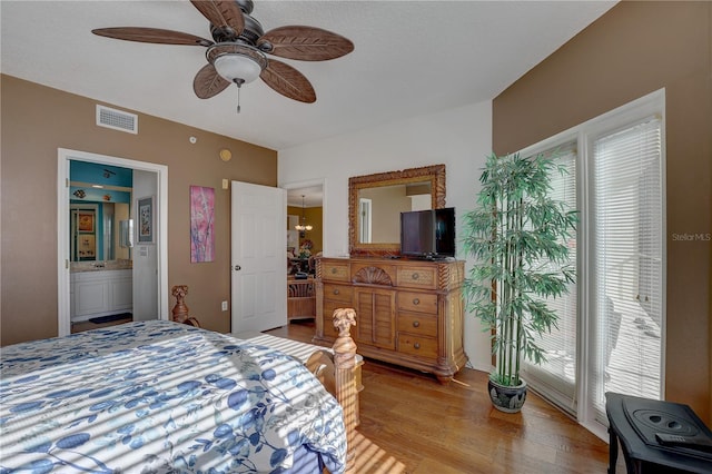 bedroom featuring ceiling fan with notable chandelier, ensuite bathroom, light hardwood / wood-style flooring, and multiple windows