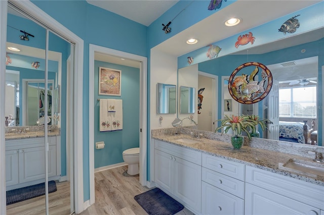 bathroom with ceiling fan, hardwood / wood-style floors, vanity, and toilet