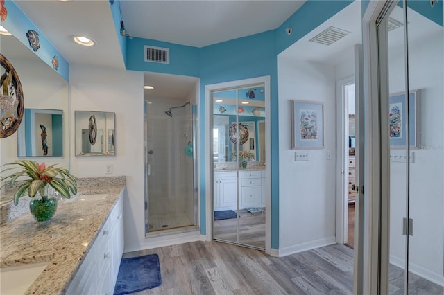 bathroom featuring hardwood / wood-style flooring, vanity, and a shower with shower door