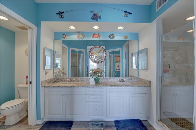 bathroom with hardwood / wood-style floors, vanity, toilet, and walk in shower