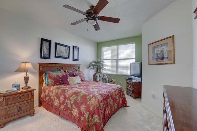 bedroom with ceiling fan, light colored carpet, and a textured ceiling