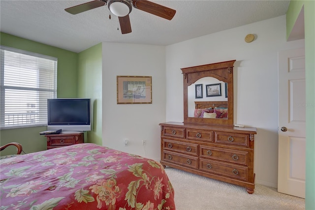 bedroom with ceiling fan, light colored carpet, and a textured ceiling