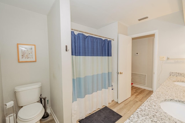 bathroom with hardwood / wood-style flooring, vanity, toilet, and walk in shower