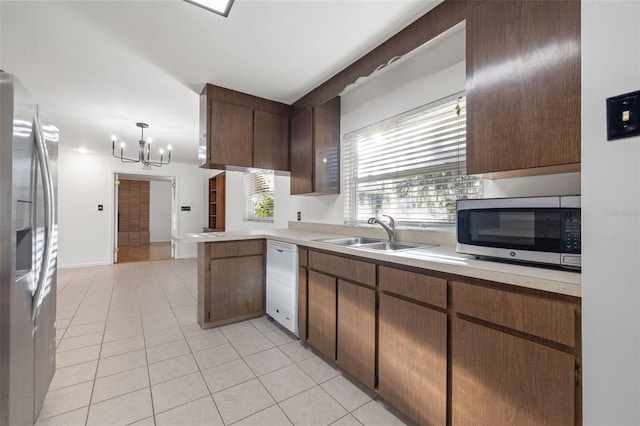 kitchen featuring appliances with stainless steel finishes, sink, an inviting chandelier, hanging light fixtures, and light tile patterned flooring