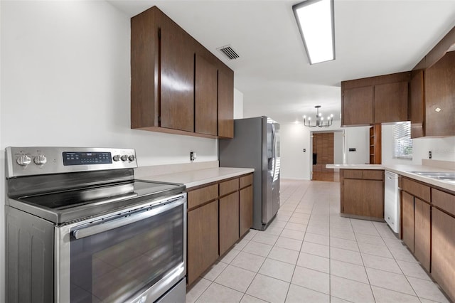 kitchen featuring kitchen peninsula, appliances with stainless steel finishes, light tile patterned floors, a notable chandelier, and hanging light fixtures