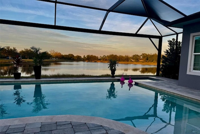 pool at dusk featuring a lanai and a water view