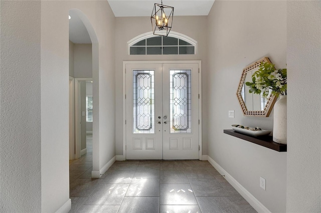 entrance foyer with a notable chandelier, a towering ceiling, and french doors