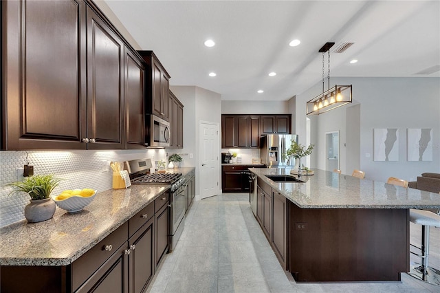 7506 Parkshore Dr, Apollo Beach, FL 33572 - kitchen featuring stainless steel appliances, decorative backsplash, dark brown cabinetry, a breakfast bar, and recessed lighting
