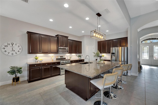 7506 Parkshore Dr, Apollo Beach, FL 33572 - kitchen featuring appliances with stainless steel finishes, stone counters, a kitchen bar, french doors, and dark brown cabinetry