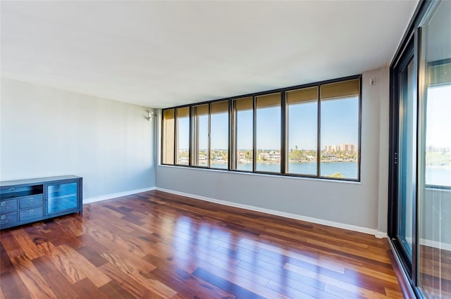 unfurnished room featuring dark hardwood / wood-style flooring and a water view