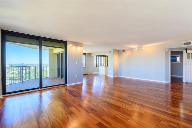 empty room featuring a barn door, wood-type flooring, and an AC wall unit