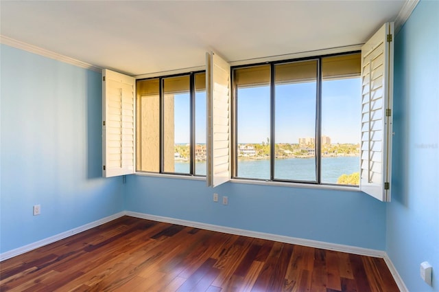 empty room featuring a water view, crown molding, and dark wood-type flooring