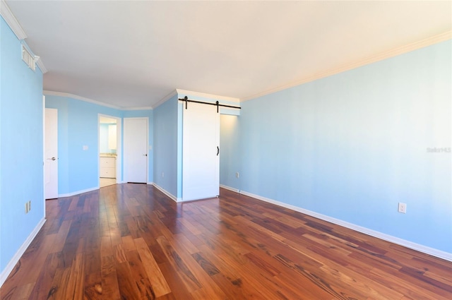 spare room featuring dark hardwood / wood-style flooring, a barn door, and ornamental molding