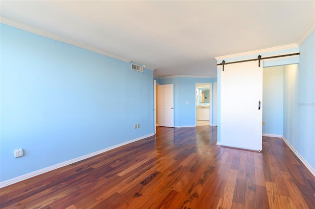 unfurnished bedroom with a barn door, dark hardwood / wood-style flooring, and ornamental molding