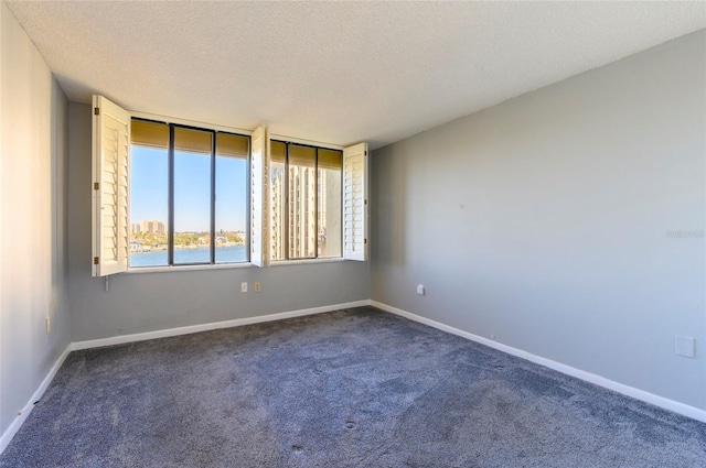 carpeted spare room with a water view and a textured ceiling