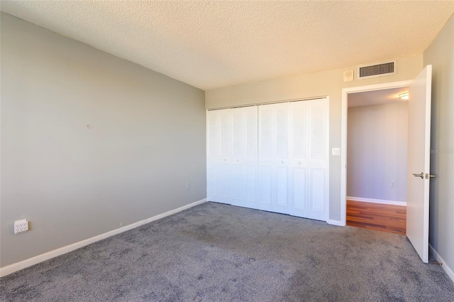 unfurnished bedroom with carpet flooring, a textured ceiling, and a closet