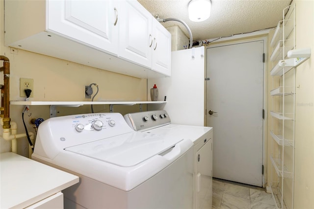 laundry room featuring washer and dryer, cabinets, and a textured ceiling