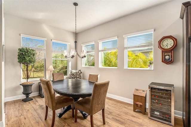 dining area with light hardwood / wood-style floors, a healthy amount of sunlight, and a notable chandelier